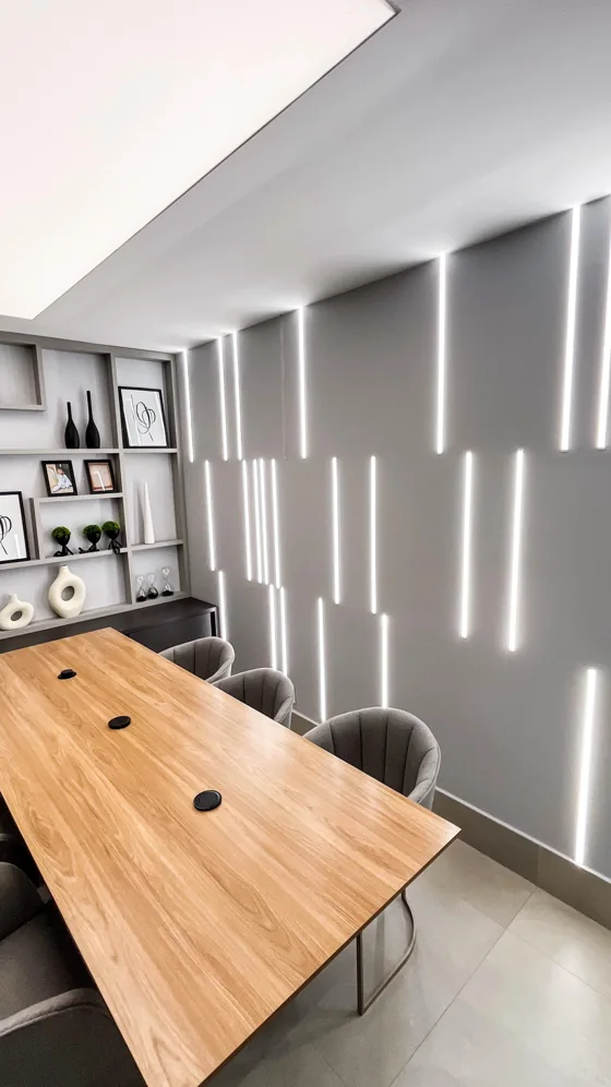 Parede em drywall com linhas verticais de iluminação em uma sala de reunião.